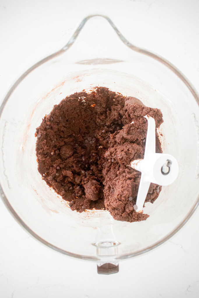 chocolate espresso cookie dough in a glass mixing bowl on a marble counter.