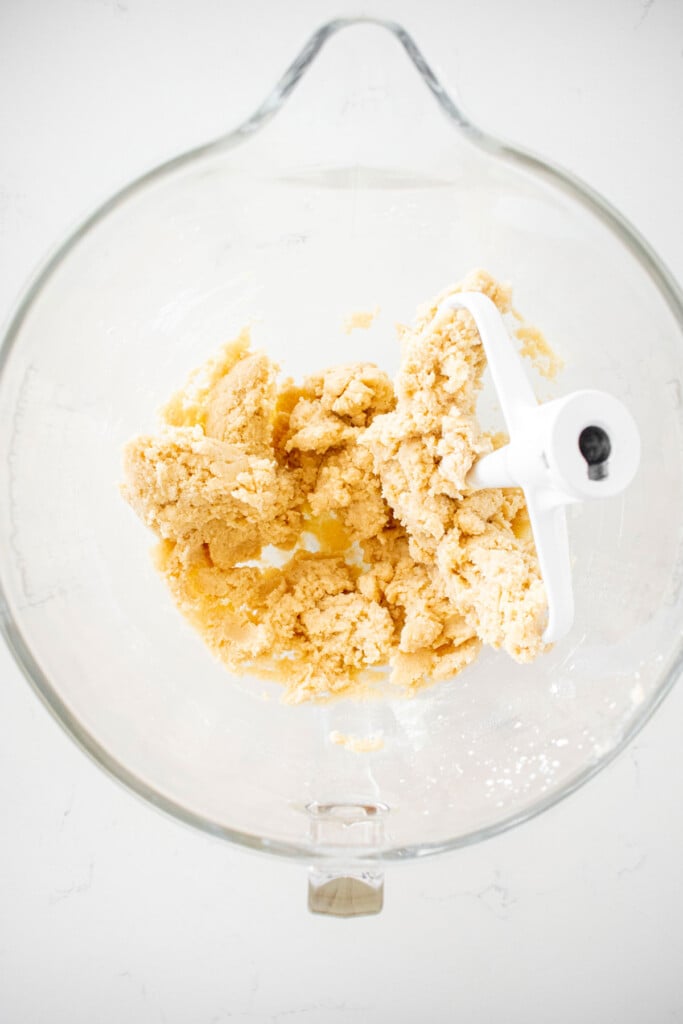 eggless chocolate chip sugar cookie dough in a glass mixing bowl on a marble counter.