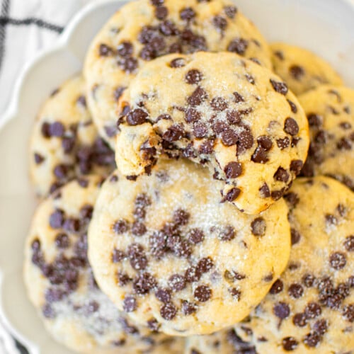 plate of eggless chocolate chip sugar cookies with a dusting of sugar on top.