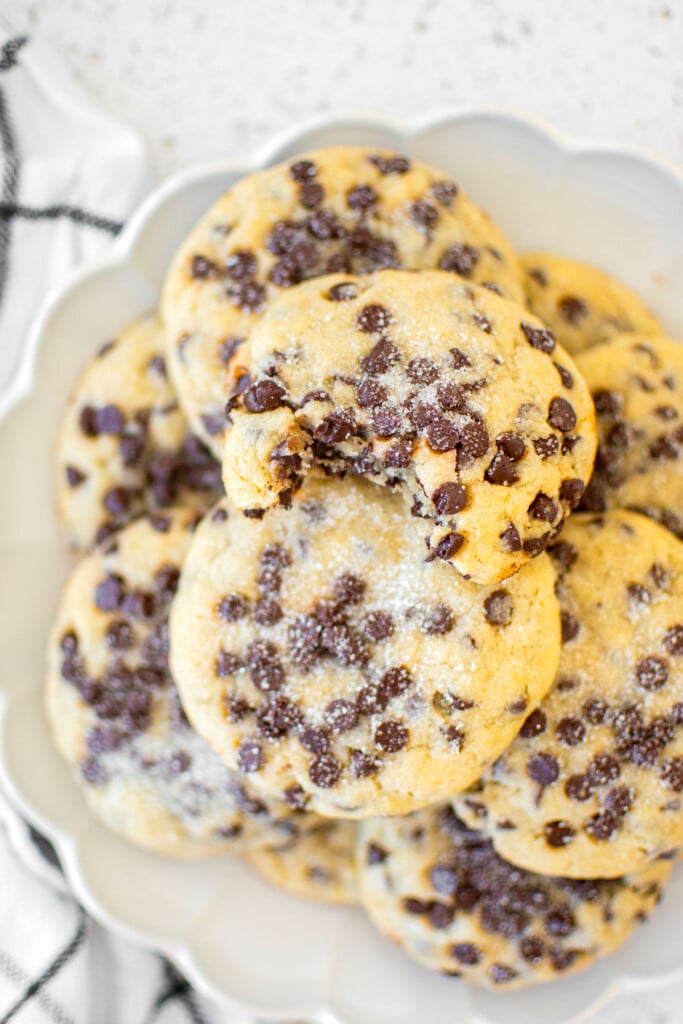 plate of eggless chocolate chip sugar cookies with a dusting of sugar on top.