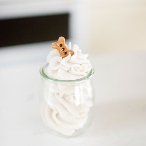 homemade pupcup with dog friendly whipped cream on the counter with a dog bone on top.