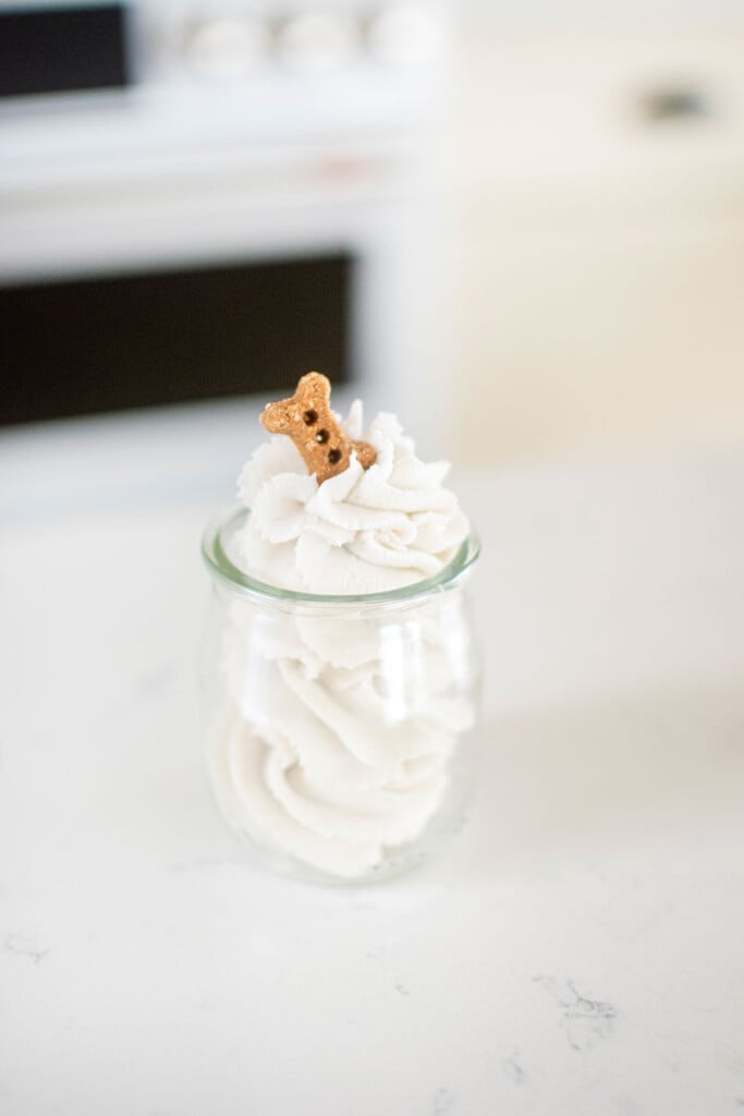homemade pupcup with dog friendly whipped cream on the counter with a dog bone on top.