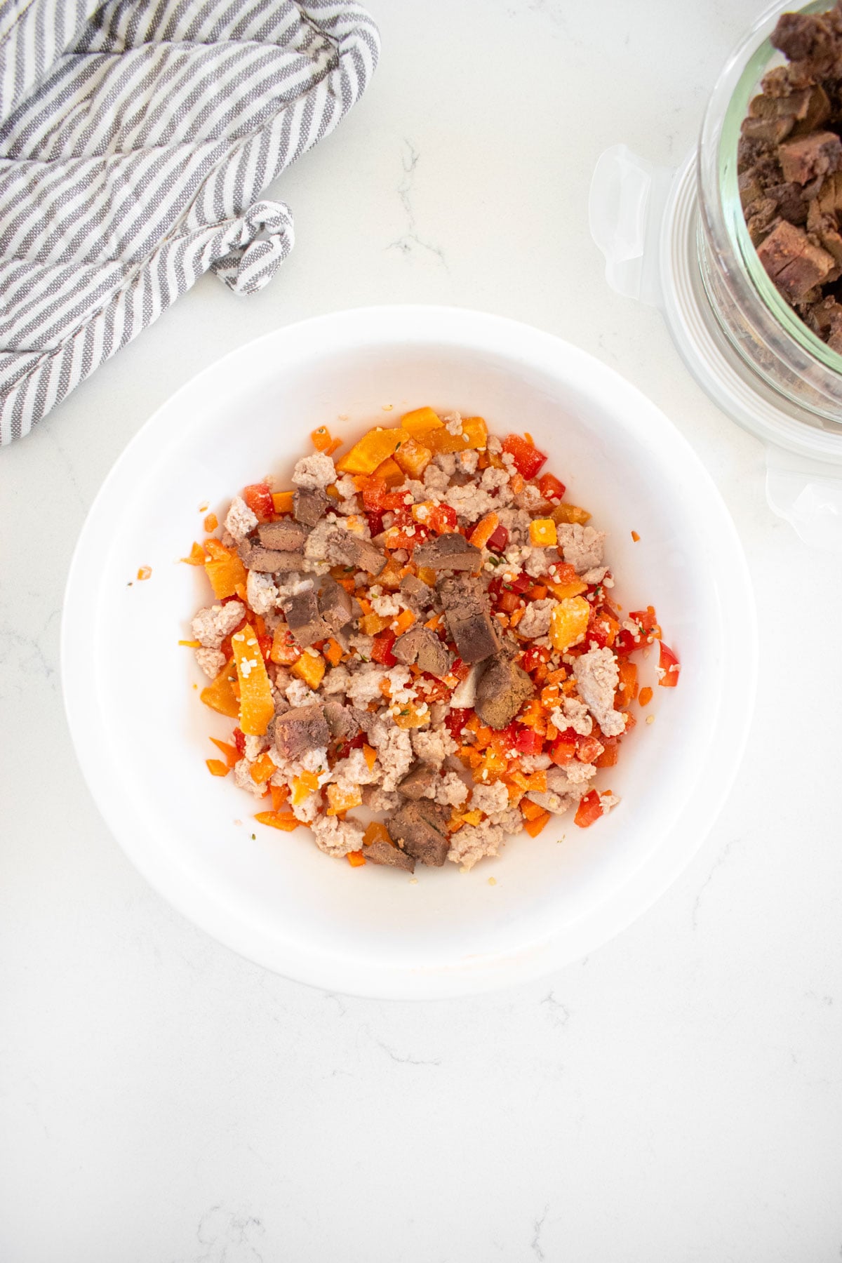 beef liver, ground turkey, carrots, red bell pepper, and sweet potato in a dogs bowl on the counter.