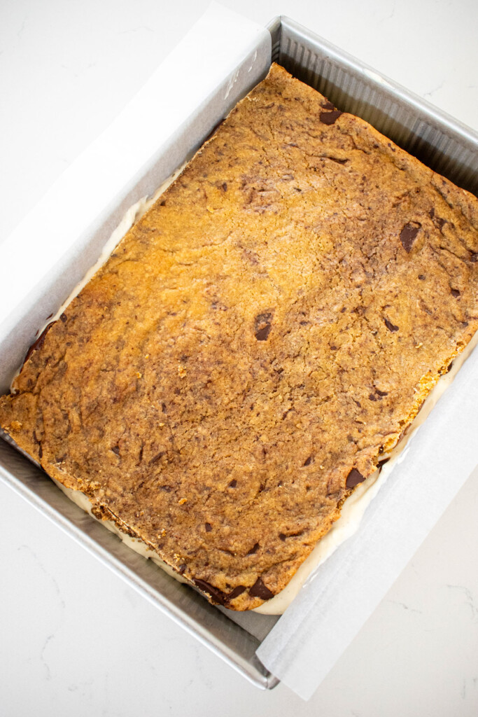 sourdough chocolate chip cookie placed on top of ice cream in a baking pan on a white marble counter.