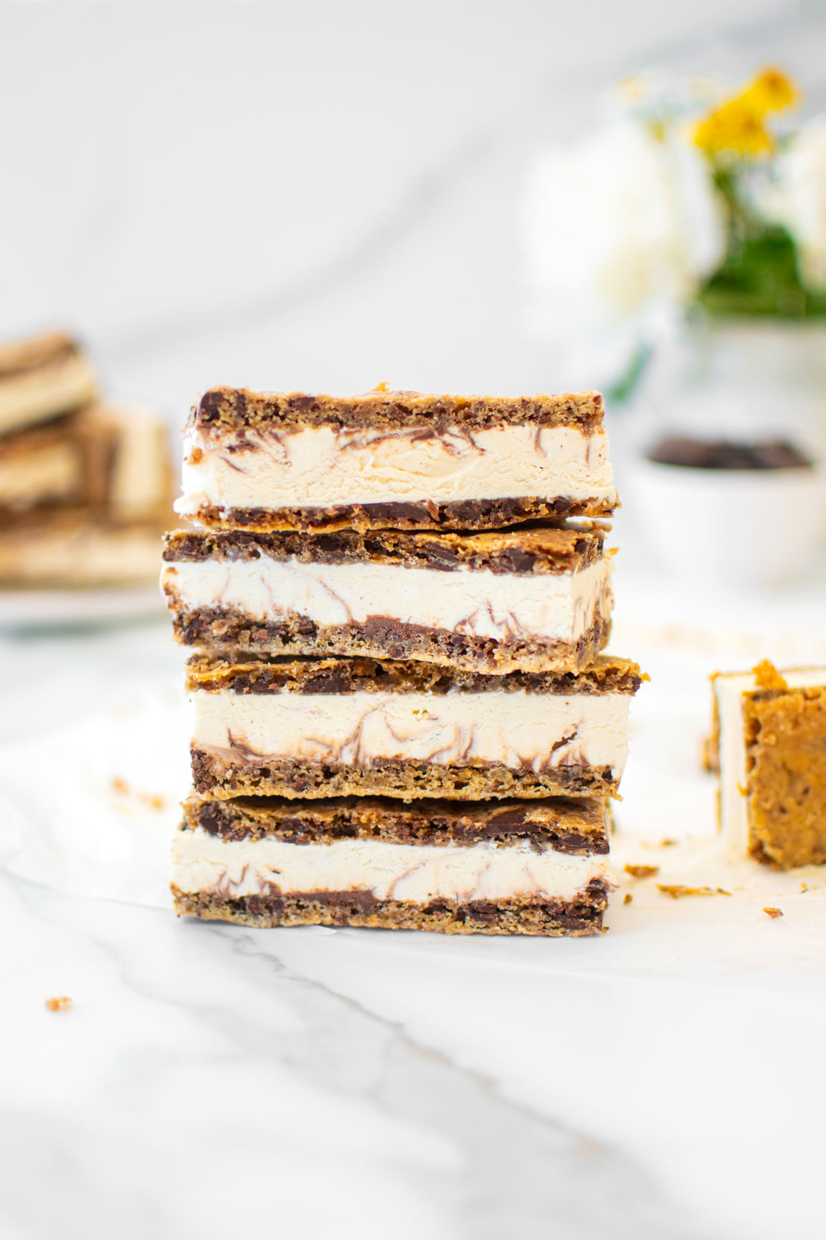 stack of sourdough chocolate chip cookie ice cream sandwiches on a white marble counter.
