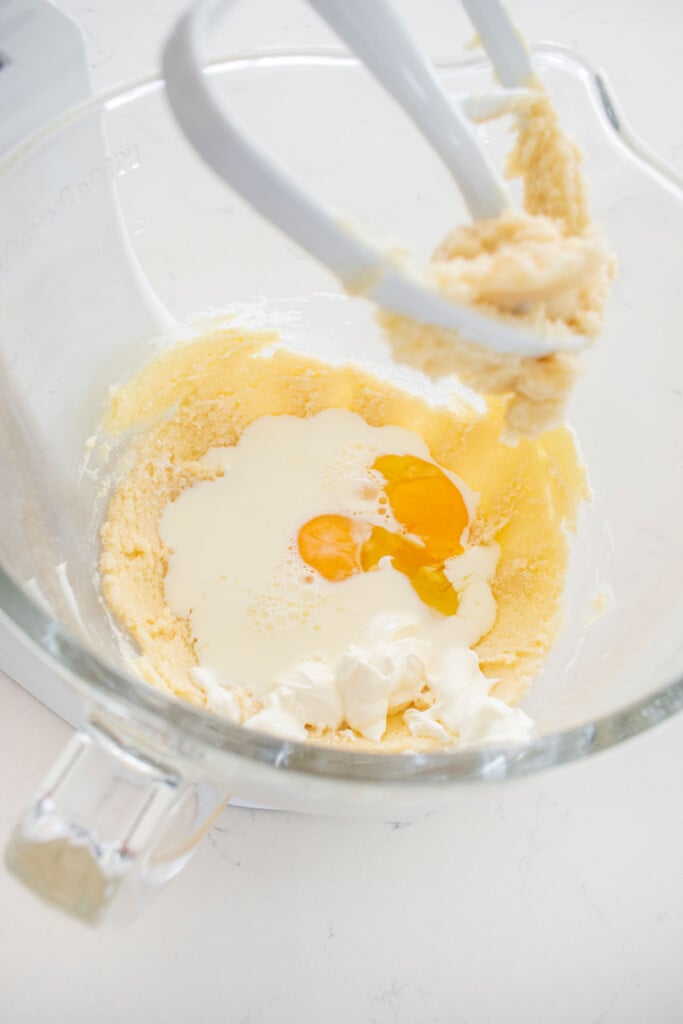 ingredients for vanilla cake in a glass mixing bowl on a white marble counter.