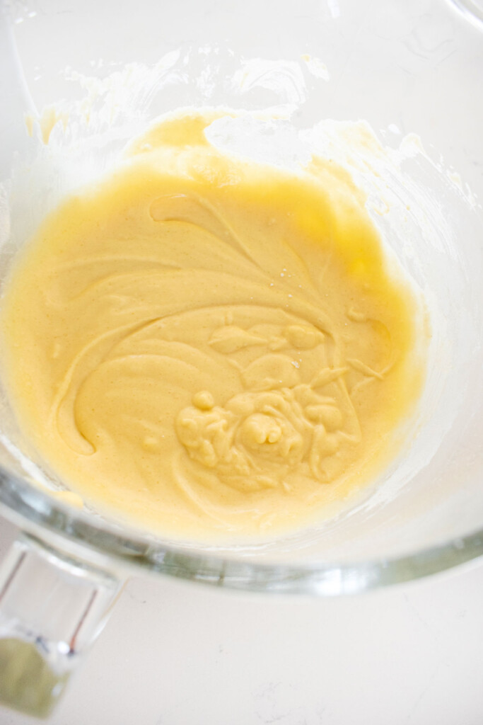 vanilla cake batter in a glass mixing bowl on a white marble counter.