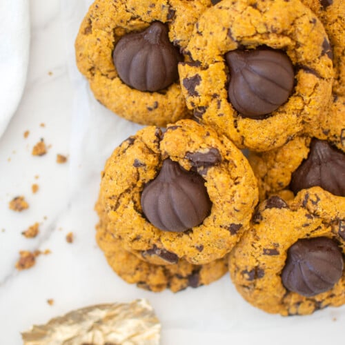 brown butter pumpkin cookies with caramel on white parchment paper on a marble counter.