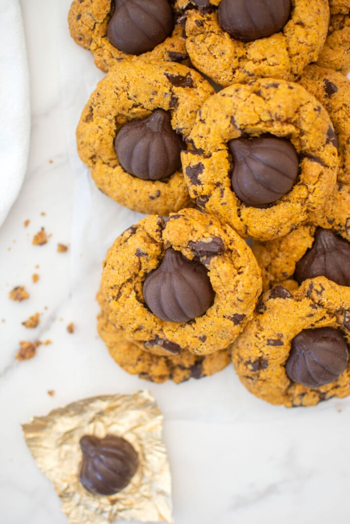 brown butter pumpkin cookies with caramel on white parchment paper on a marble counter.