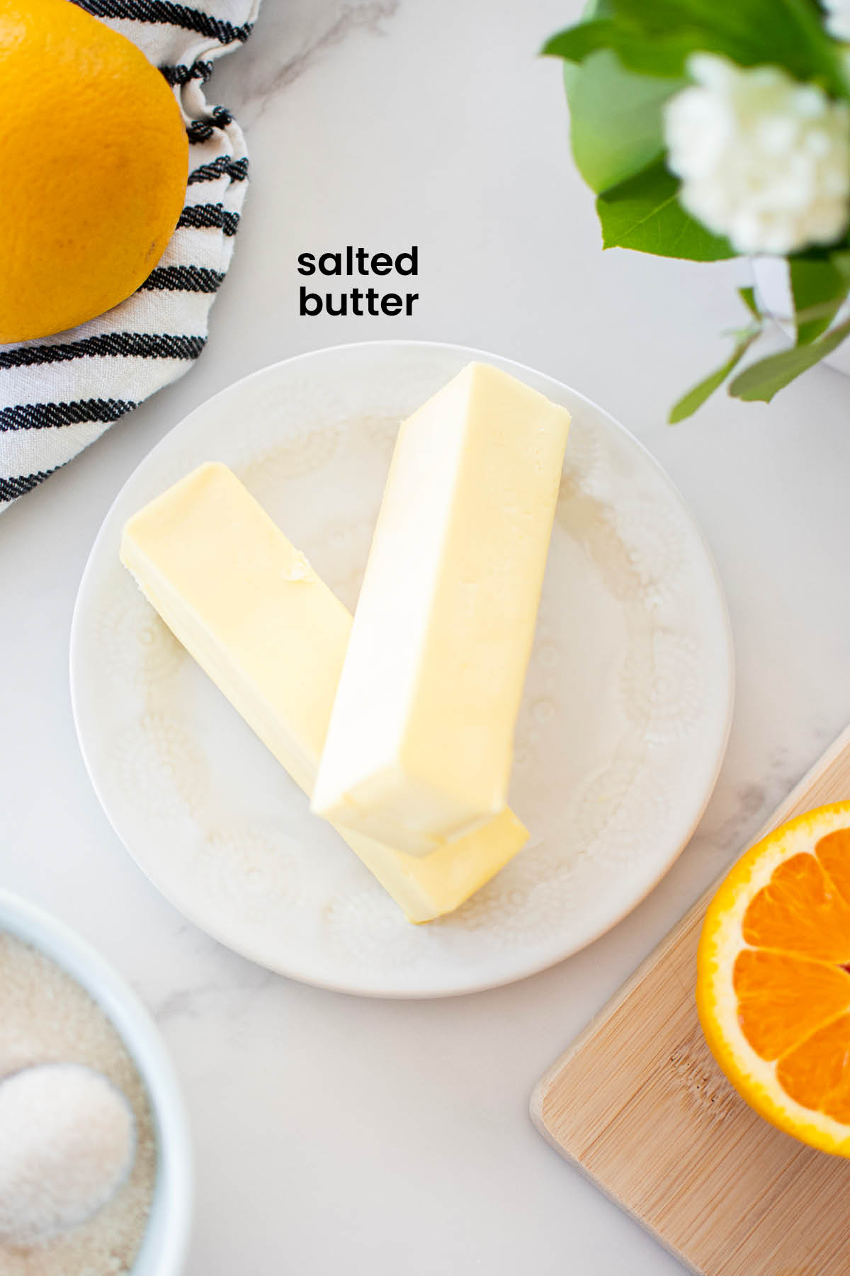 butter sticks on a white plate on a marble counter.