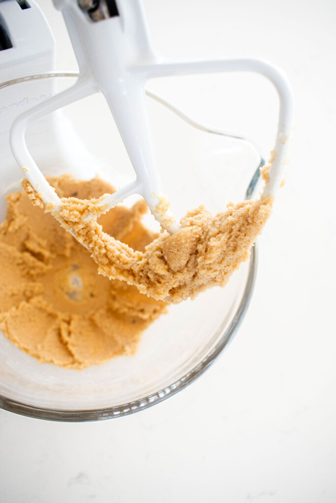 creamed butter and sugar in a glass mixing bowl on a white marble counter.