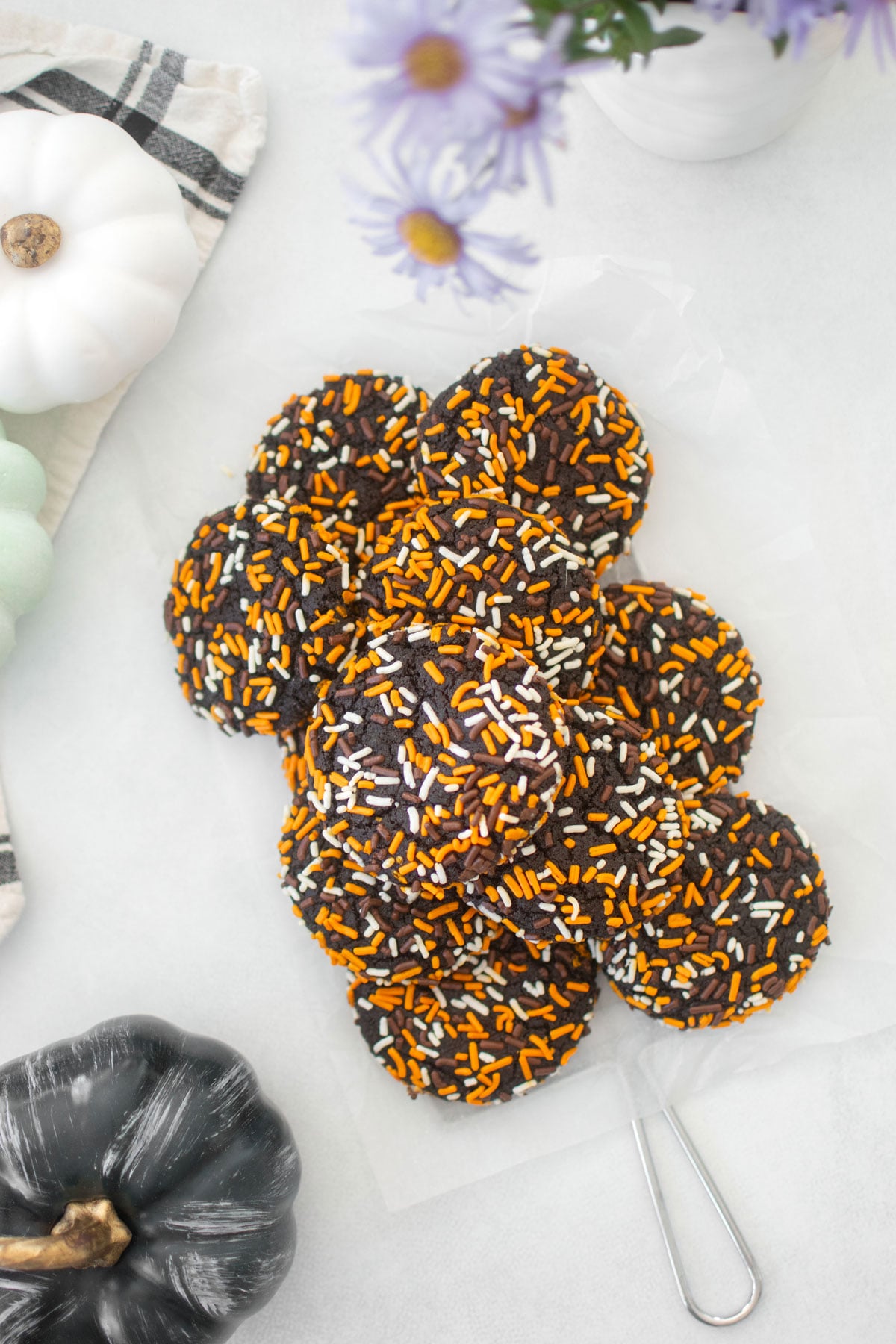 organic halloween cookies on a cooling rack on a white marble counter with flowers and pumpkins.