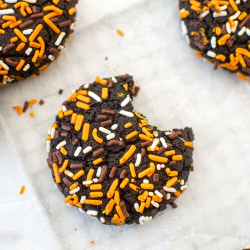 organic halloween cookies with sprinkles on a white marble counter, one with a bite taken out.