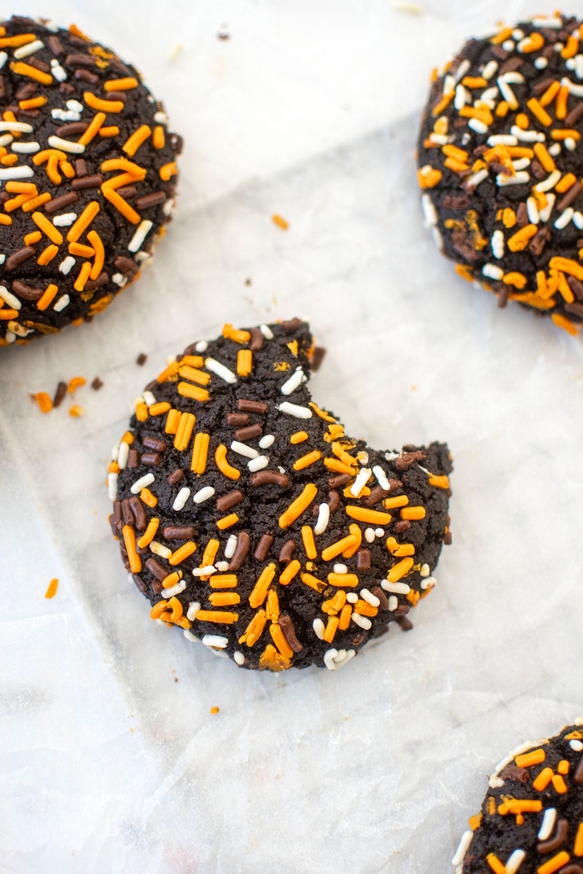 organic halloween cookies with sprinkles on a white marble counter, one with a bite taken out.