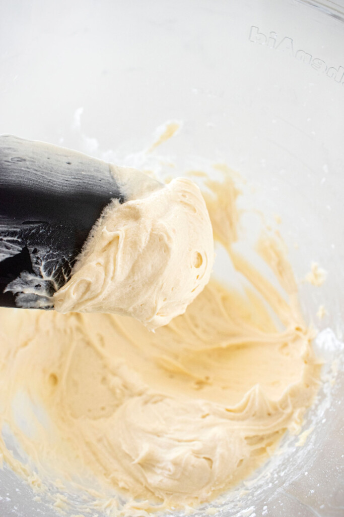 white buttercream frosting in a glass mixing bowl.