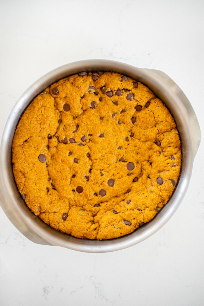 baked pumpkin chocolate chip cookie cake on a white marble counter.