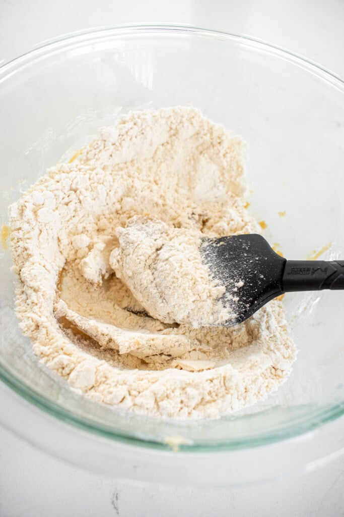 ingredients for maple brown sugar cookies in a glass bowl on a white marble counter.