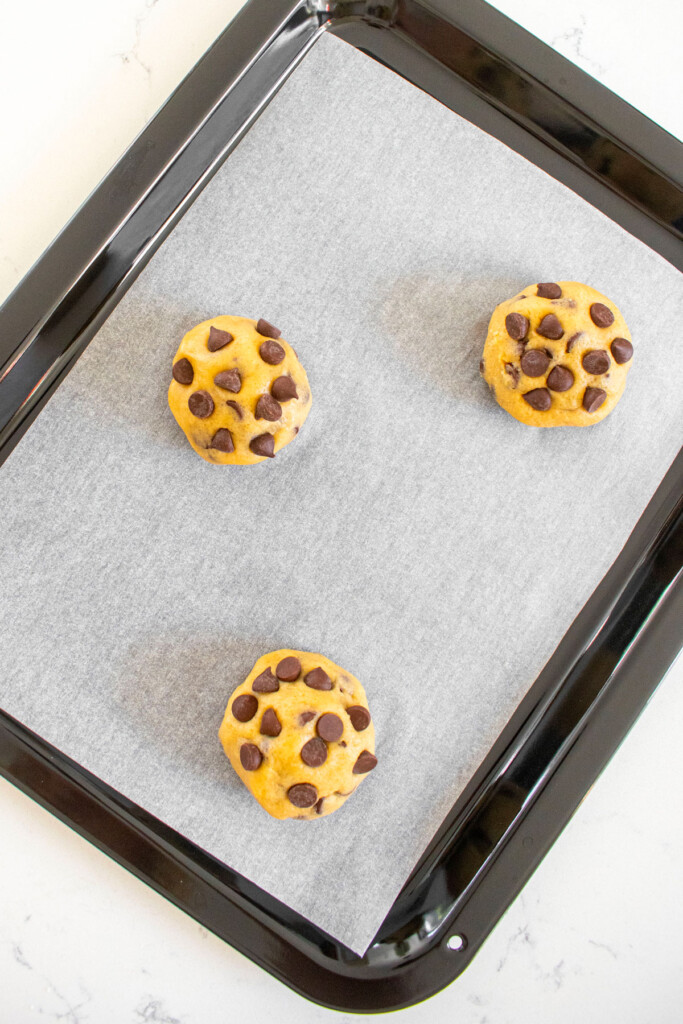small batch maple brown sugar cookie dough rolled into 3 balls on a countertop oven tray on a white marble counter.