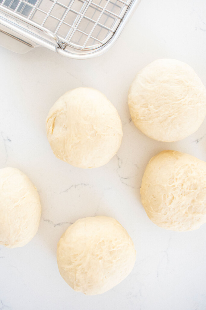 sourdough pretzel bun dough on a white marble counter.