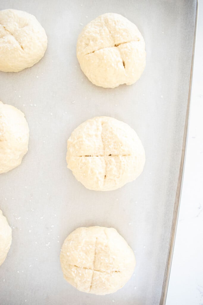 raw sourdough pretzel buns on a baking sheet.