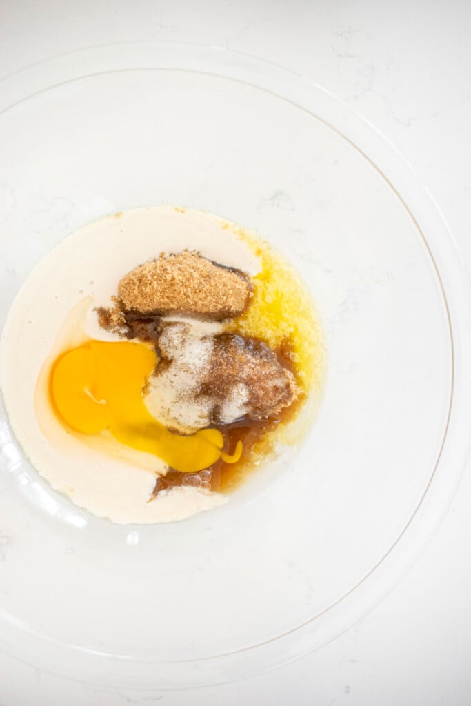 wet ingredients for chai donuts in a glass mixing bowl on a white marble counter.