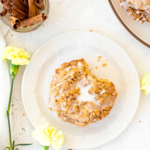 baked chai donut with sourdough discard with a bite taken out on a white plate on a stone counter.