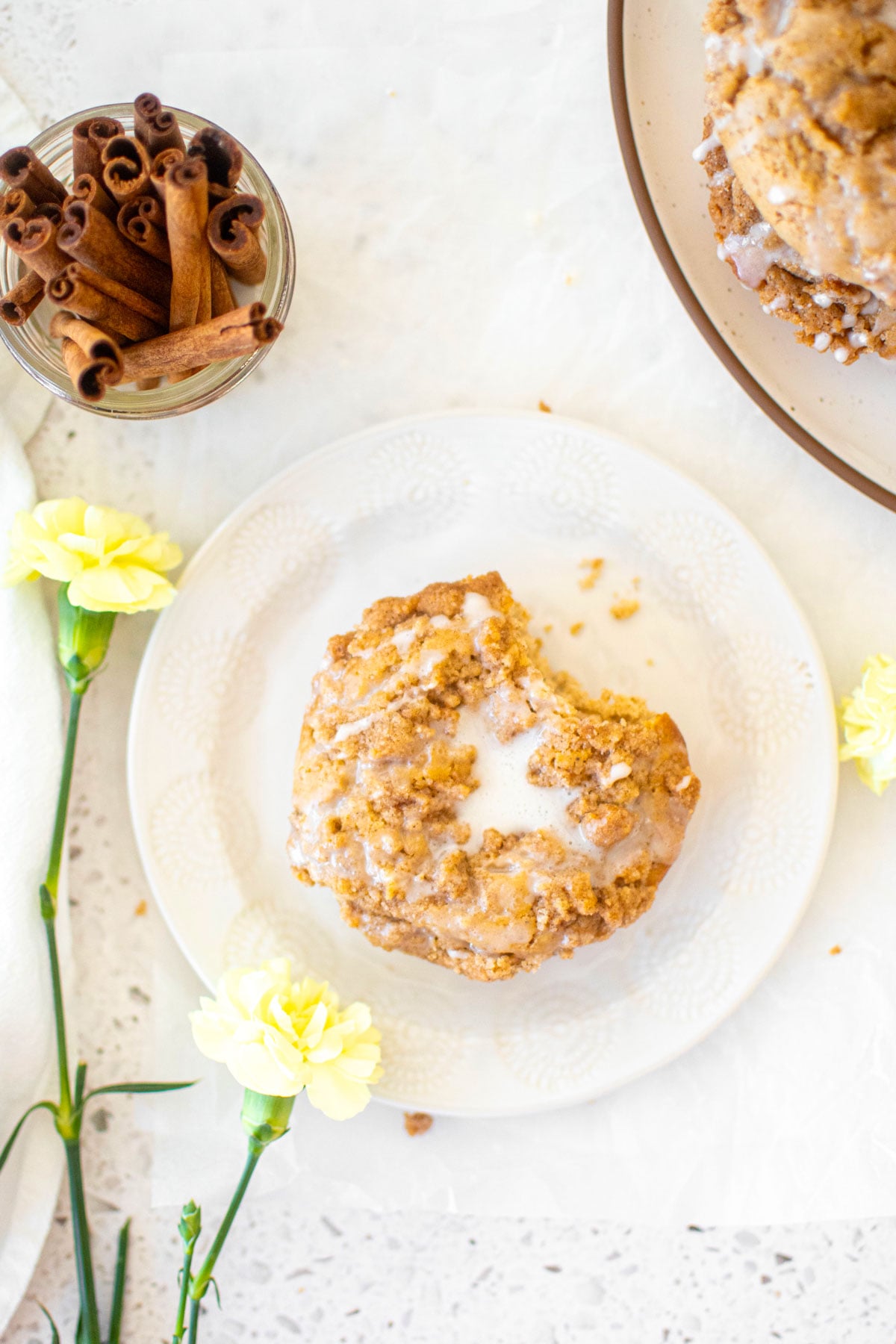 baked chai donut with sourdough discard with a bite taken out on a white plate on a stone counter.
