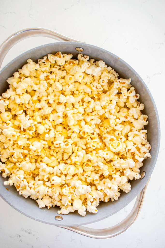 popped popcorn in a large stock pot on a white marble countertop.