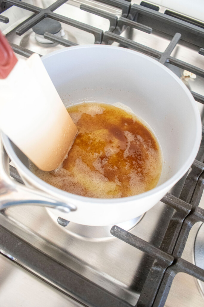 brown butter in small saucepan on the stovetop being stirred with a spatula.