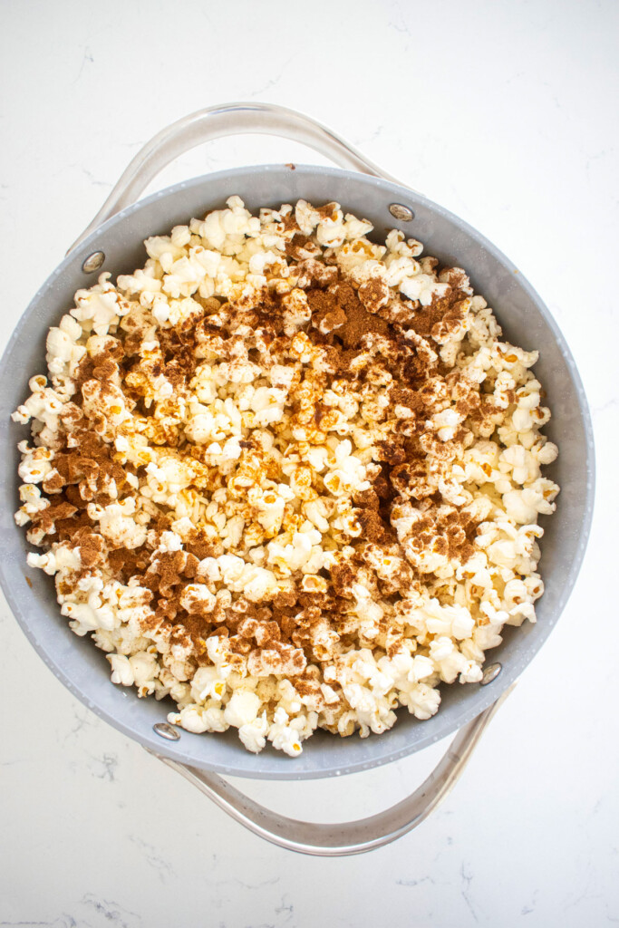 popped corn in a large stock pot with brown butter and pumpkin spice on top.