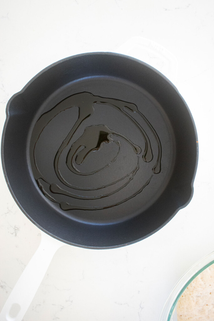 olive oil in a cast iron skillet on a white marble counter.