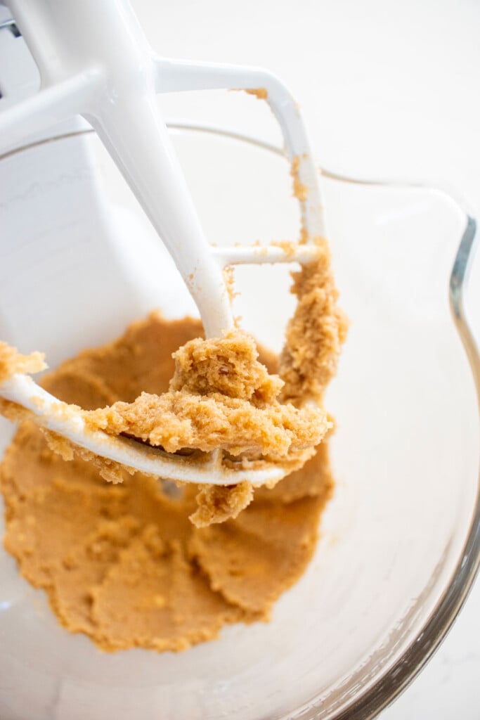 creamed butter and sugar in a glass mixing bowl on a white marble counter.