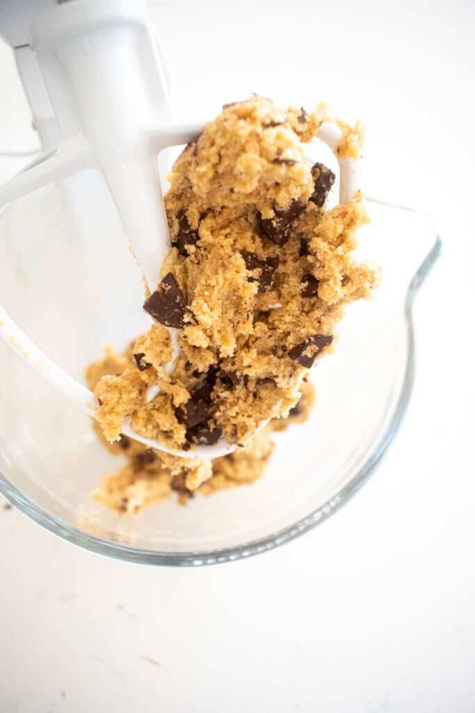crunch bar cookie dough in a glass mixing bowl on a white marble counter.
