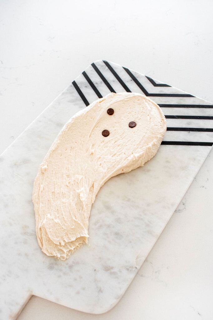 ghost frosting on a board on a white marble counter.