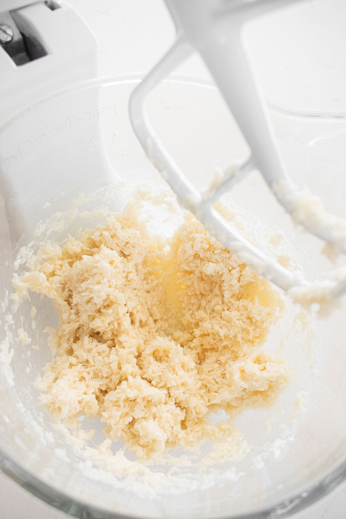 almond joy filling mixed together in a glass mixing bowl on a white marble counter.