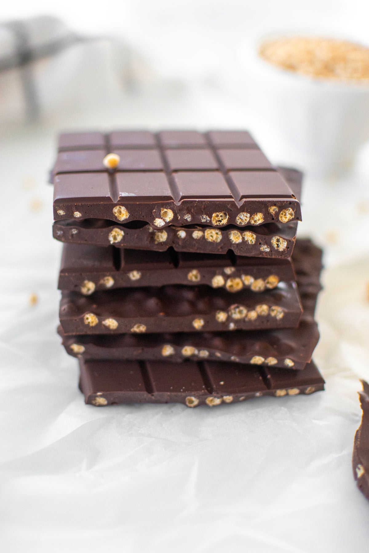 stack of homemade crunch bars broken in half on white parchment paper.