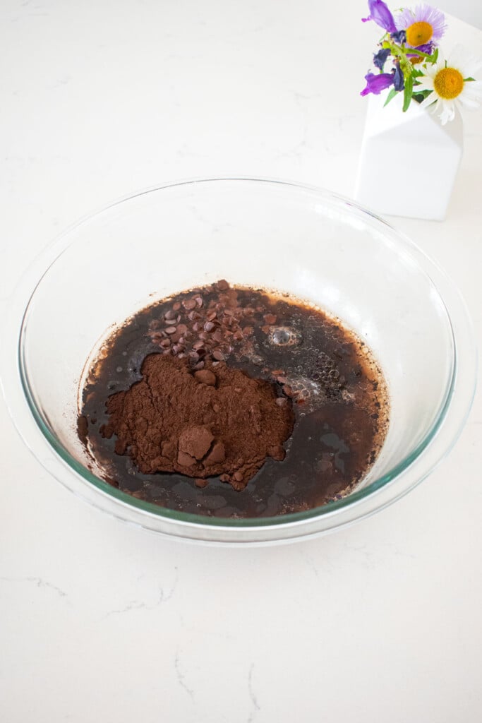 wet ingredients for brownies in a glass mixing bowl on a marble counter.