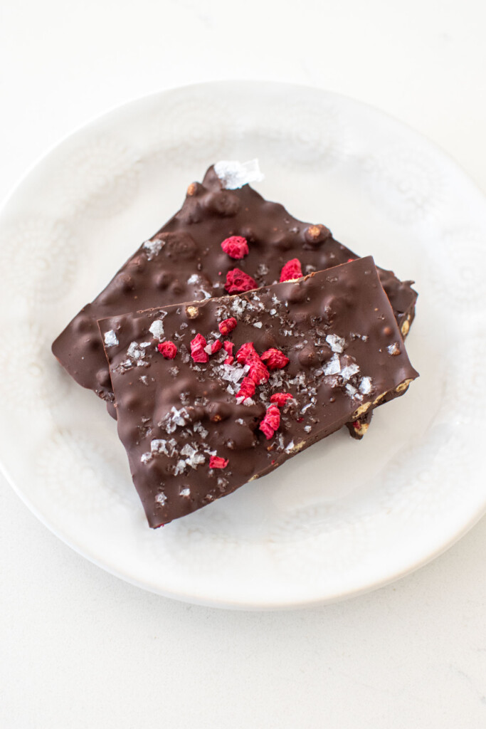 two pieces of raspberry crunch bars on a white plate on a marble counter.