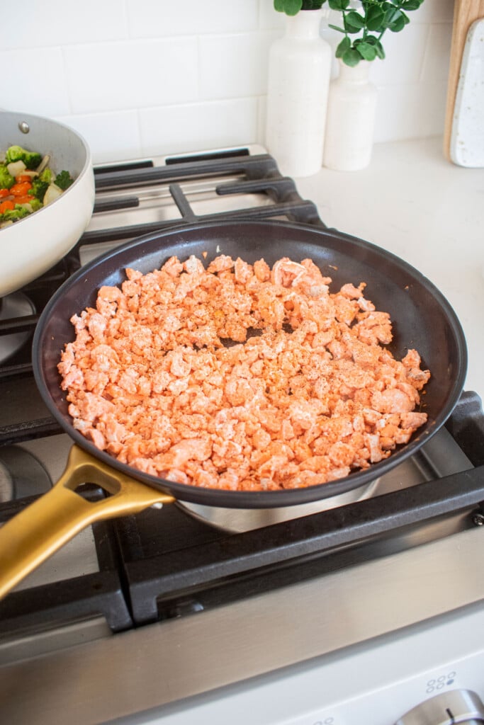 large skillet with ground salmon being cooked over the stovetop.