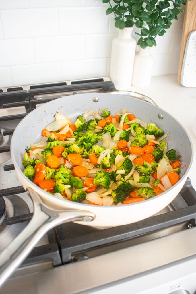 skillet with veggies, garlic, and ginger being cooked over the stovetop.