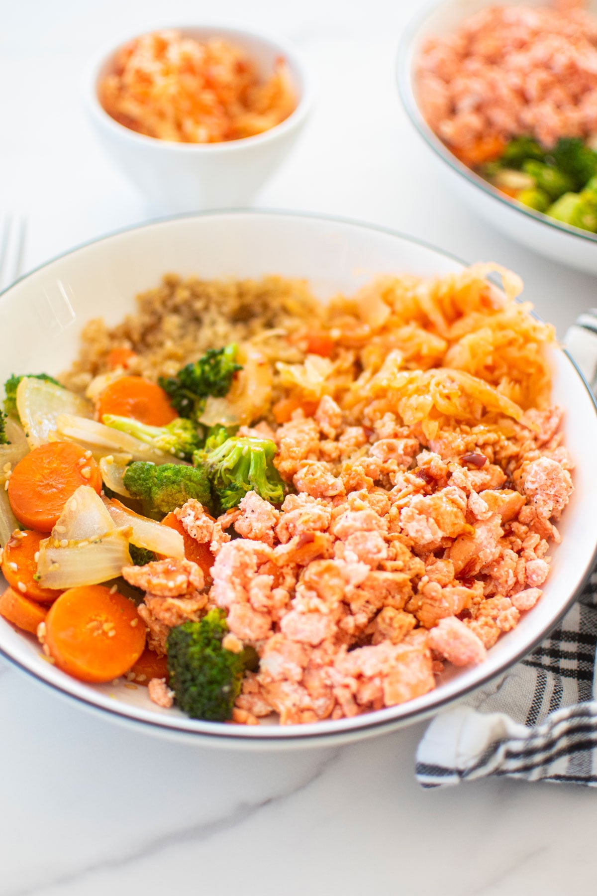 sesame ginger salmon bowl with quinoa on a white marble countertop.