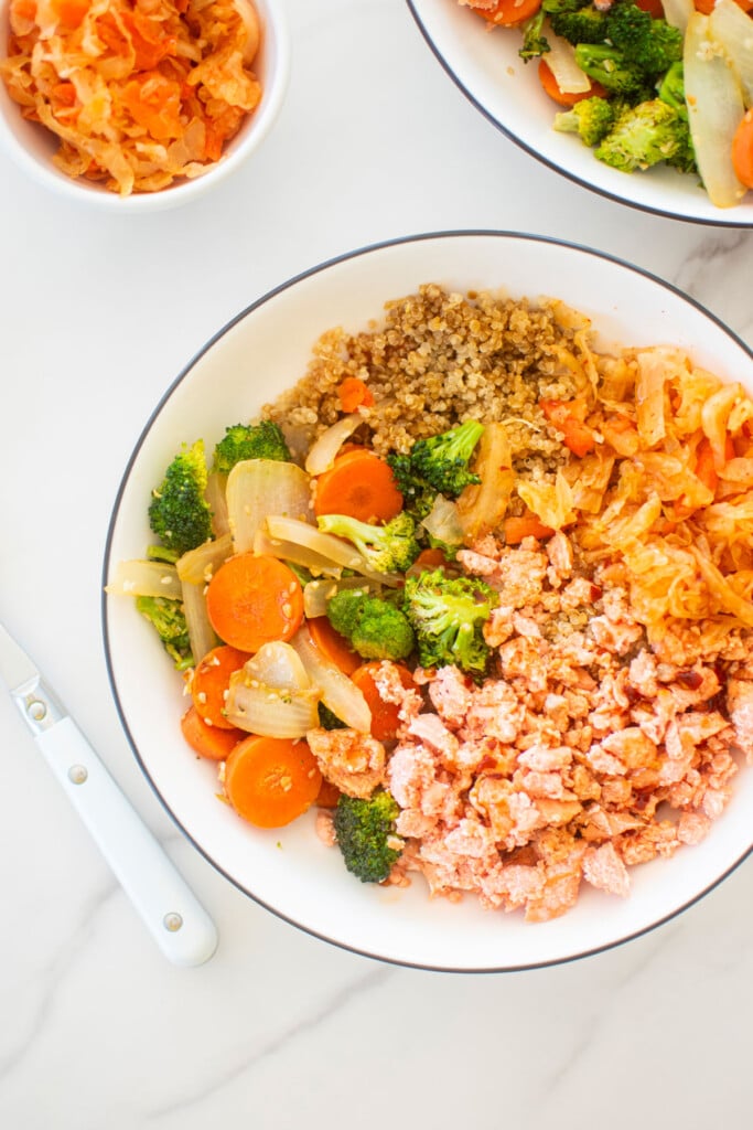 sesame ginger salmon bowl with quinoa on a white marble countertop.