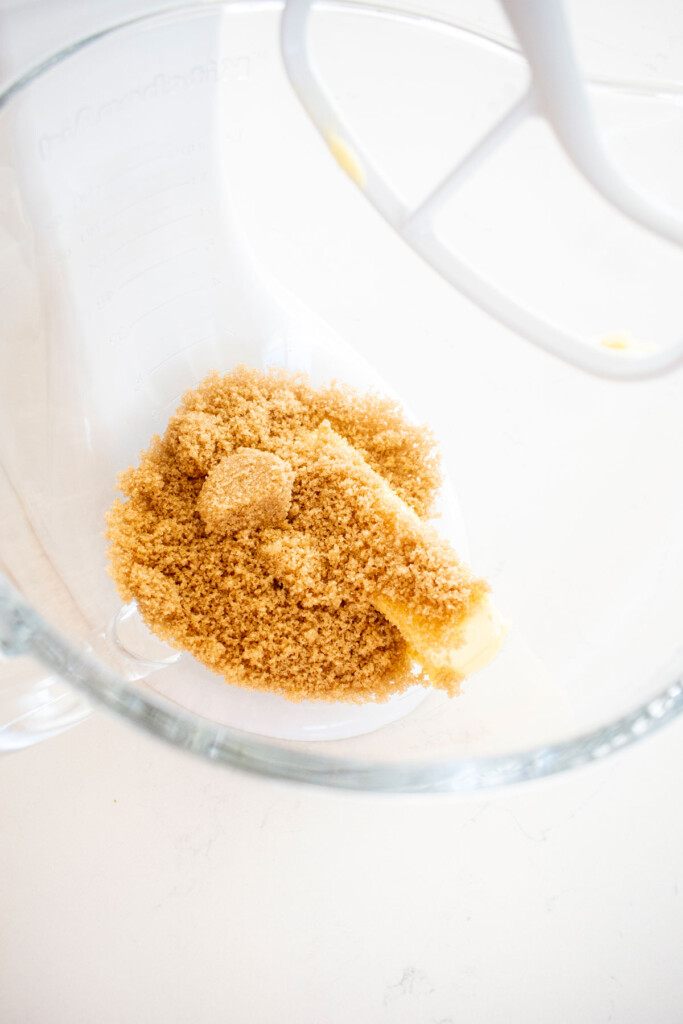 vegan butter with light brown sugar in a glass mixing bowl on a white marble counter.
