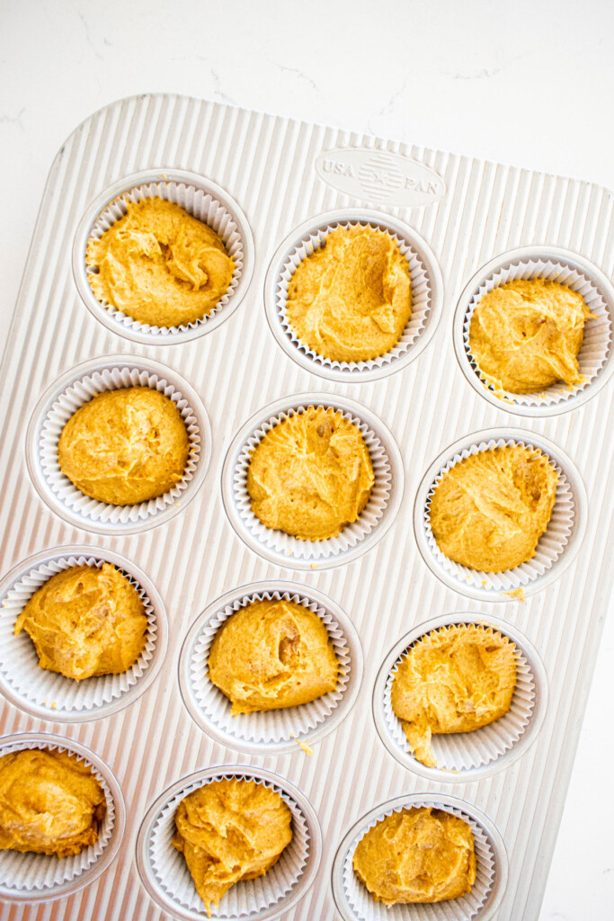 vegan pumpkin cupcake batter in a cupcake pan on a white marble counter.