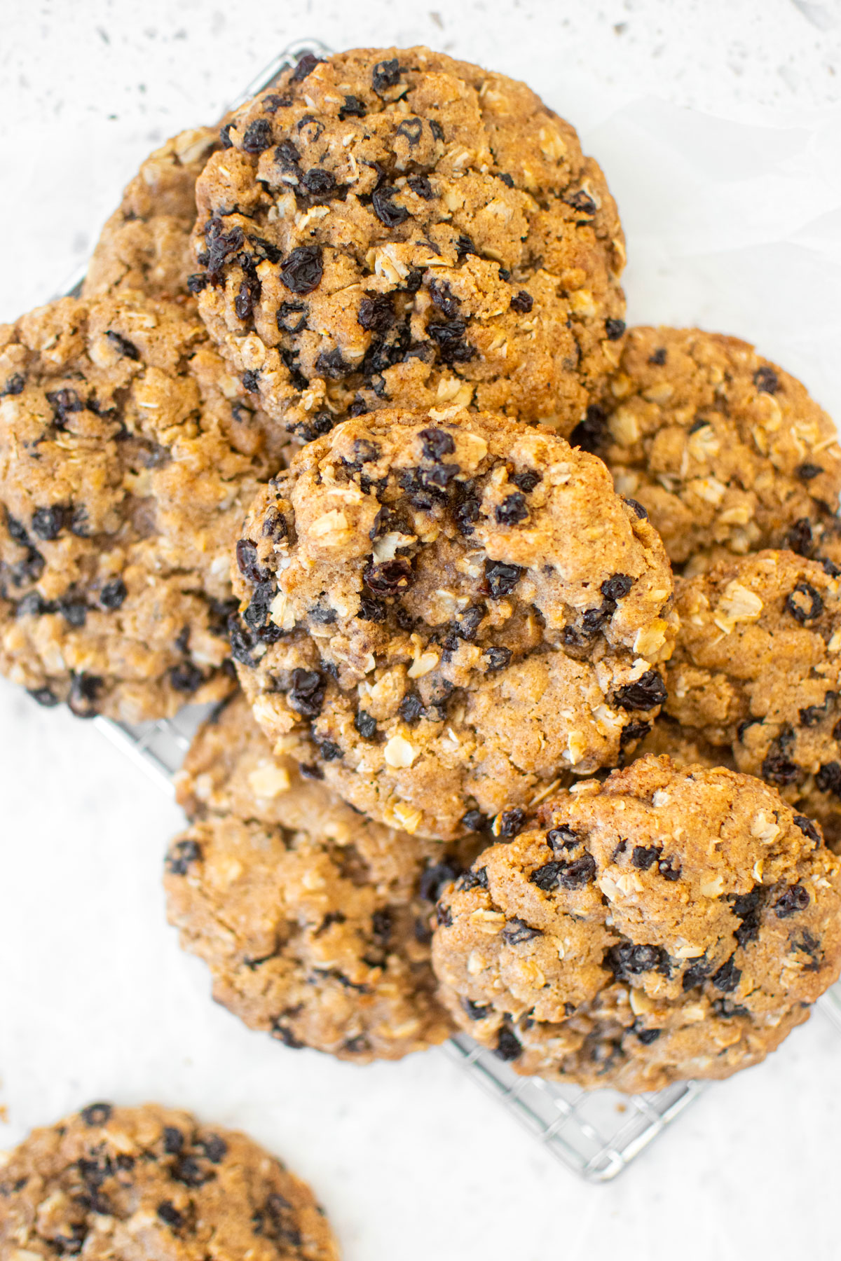vegan spiced oatmeal raisin cookies on a cooling rack on a white marble counter.