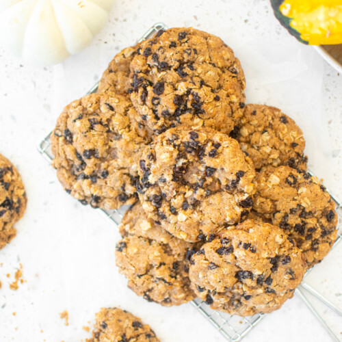 vegan spiced oatmeal raisin cookies on a cooling rack on a white marble counter.