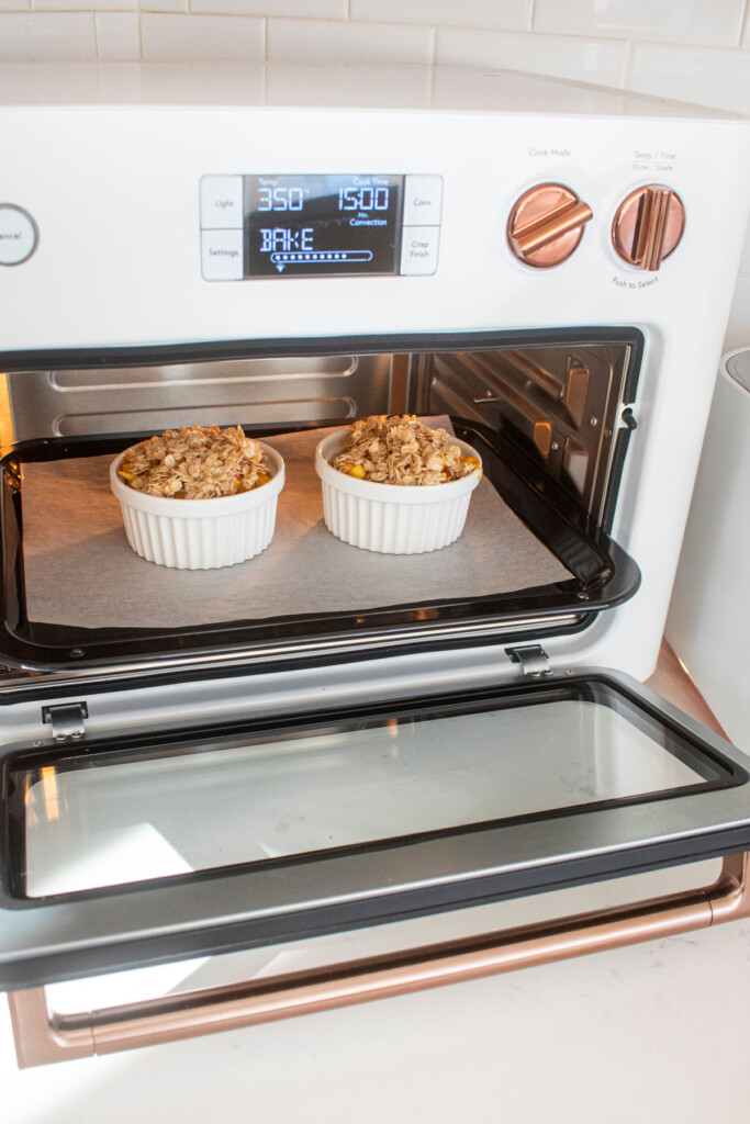apple crisp for dogs in two white ramekins in a white toaster oven on the countertop.