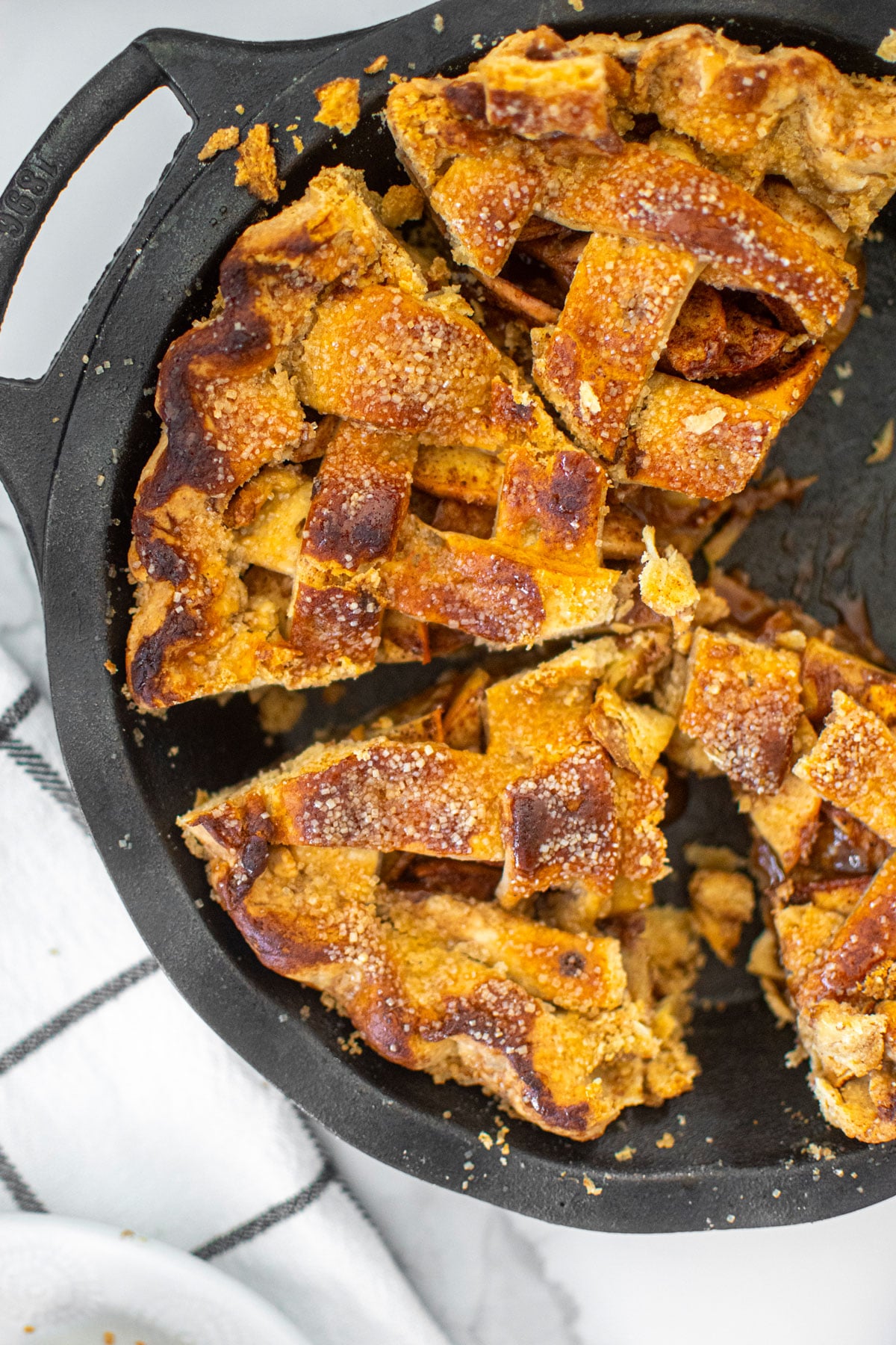 brown butter apple pie in a cast iron pie pan cut into slices.