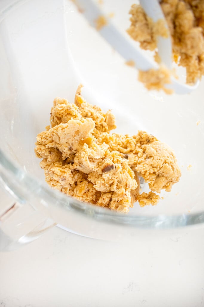 brown butter pie crust in a glass mixing bowl on a white marble counter.