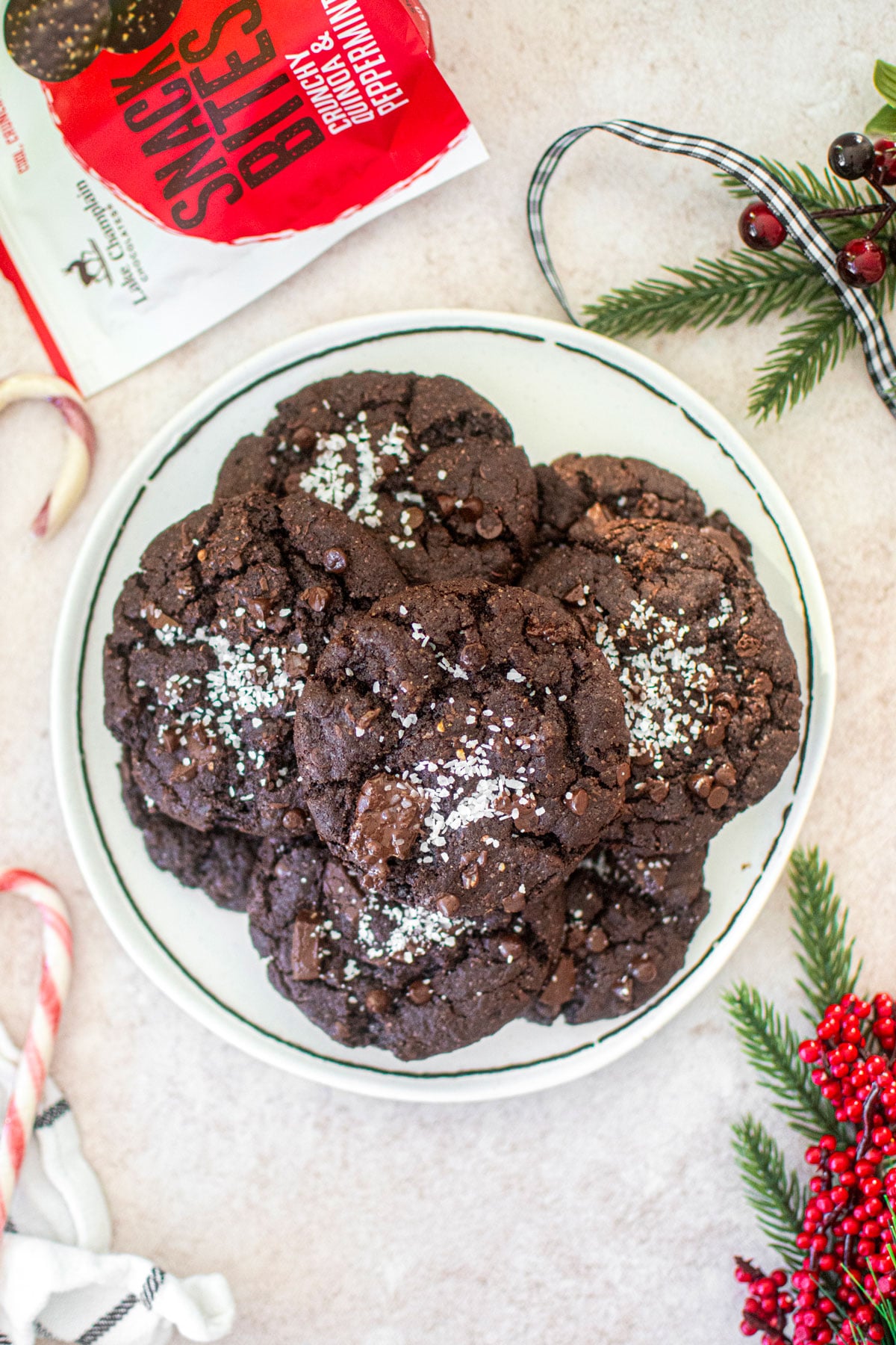 chocolate peppermint crunch cookies on a white plate with candy canes and festive greens around.